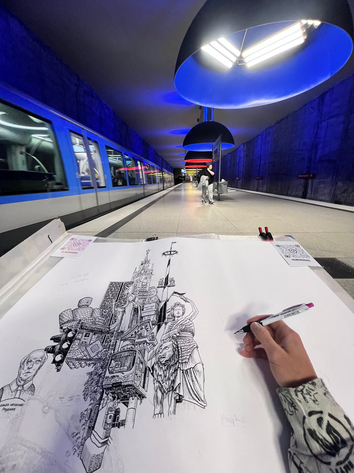 Heiner Radau zeichnet das Muenchen-Kunstwerk live am U-Bahnhof Westfriedhof, mit den ikonischen blauen Ingo-Maurer-Lampen und einer U-Bahn daneben.