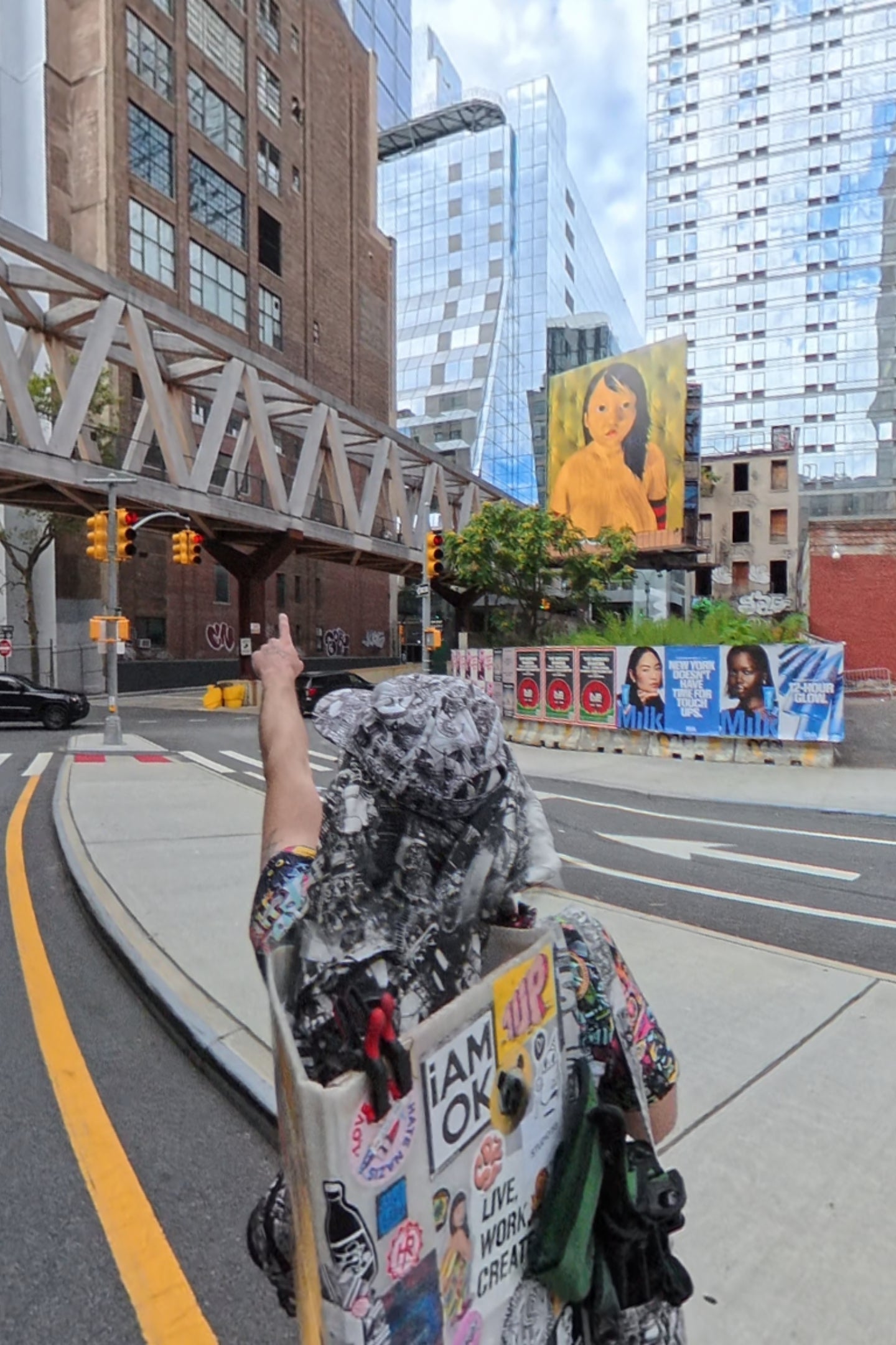 Person taking a selfie on a NYC city street with buildings and road signs in the background (highline start nyc)
