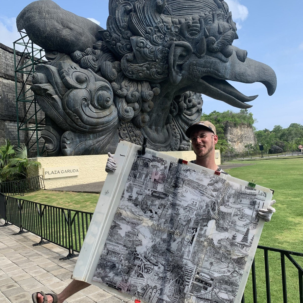 Heiner Radau holding his drawing in front of the Garuda statue in Bali.