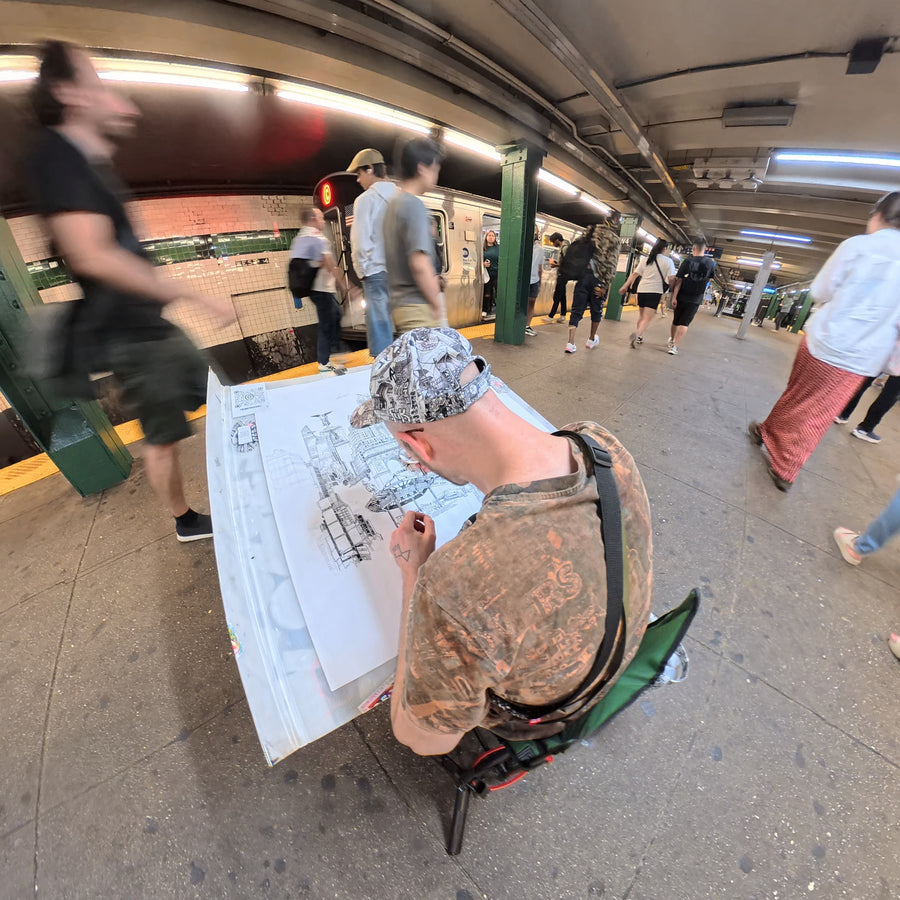 Heiner Radau drawing the large NYC artwork by hand on a New York subway platform with train and commuters passing by.