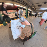 Heiner Radau drawing the large NYC artwork by hand on a New York subway platform with train and commuters passing by.
